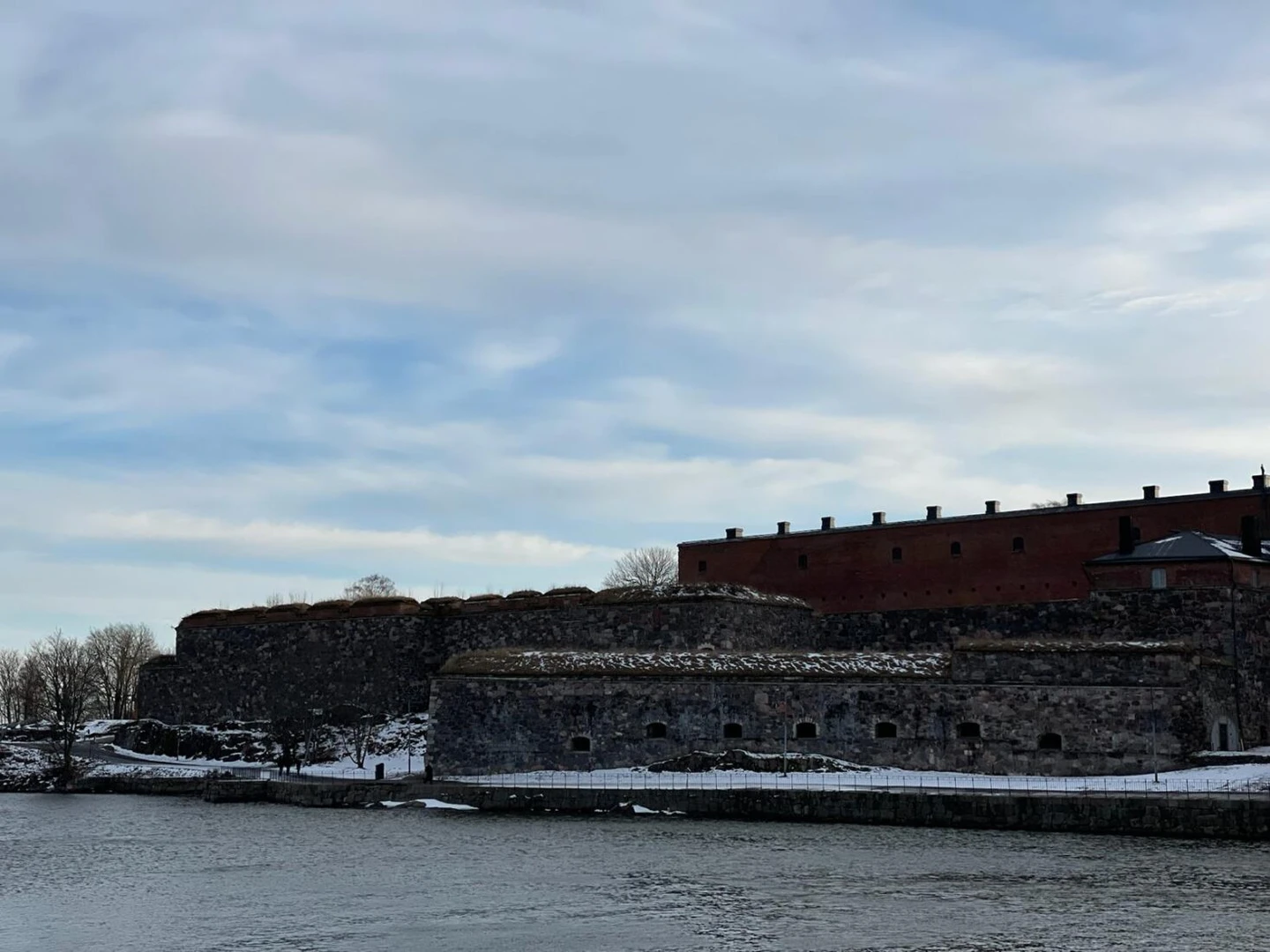 A scenic view of the coastline of Suomenlinna Island, with icy waters and rugged natural beauty.