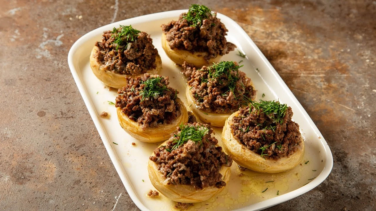 A plate of Turkish-style stuffed artichokes filled with spiced ground meat and garnished with fresh herbs.