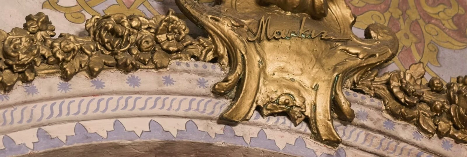 A close-up of the Markiz Pastanesi emblem, showing an ornate golden inscription surrounded by floral carvings and decorative patterns.