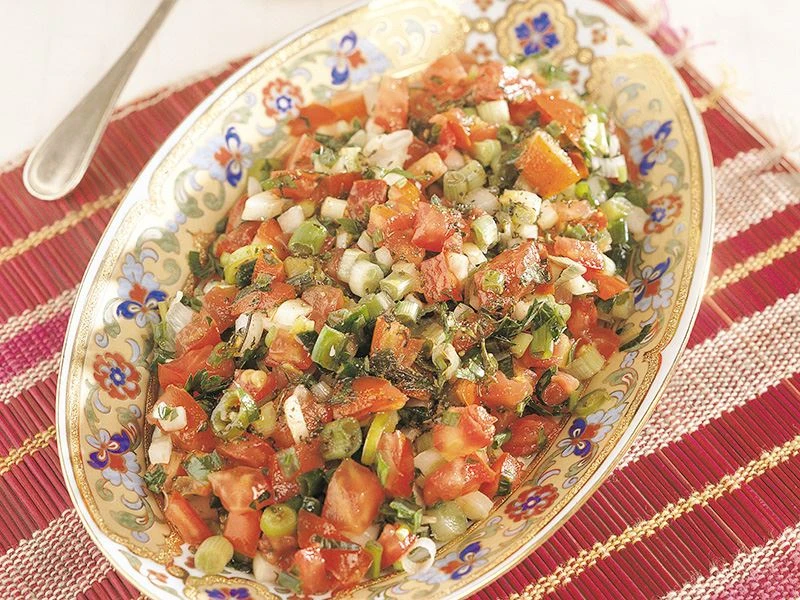 A colorful Turkish pomegranate salad with walnuts, fresh herbs, and diced vegetables served in a decorative bowl.