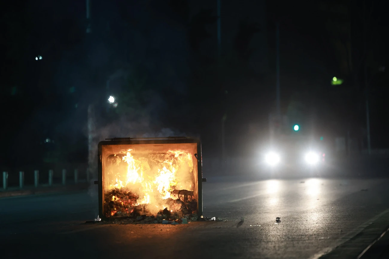 A trash bin is set on fire in the middle of the road during demonstrations over the Tempi train disaster, Athens, Greece, Mar. 5, 2025. (Courtesy of in.gr)